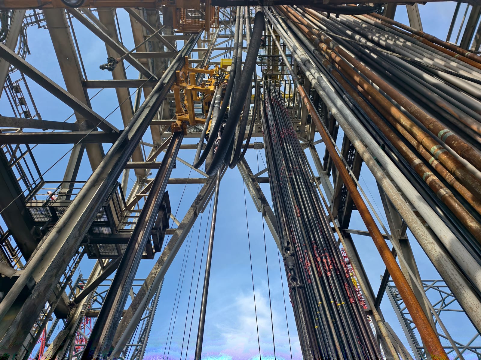 View up an Anoha drilling derrick against a blue sky